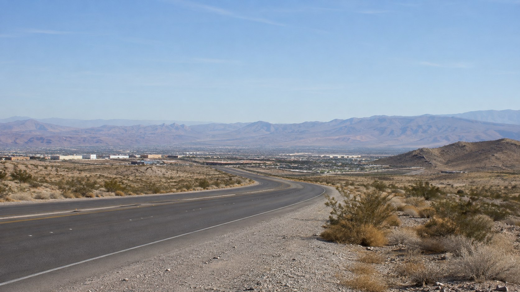 Desert roadway descending toward a valley and mountain range